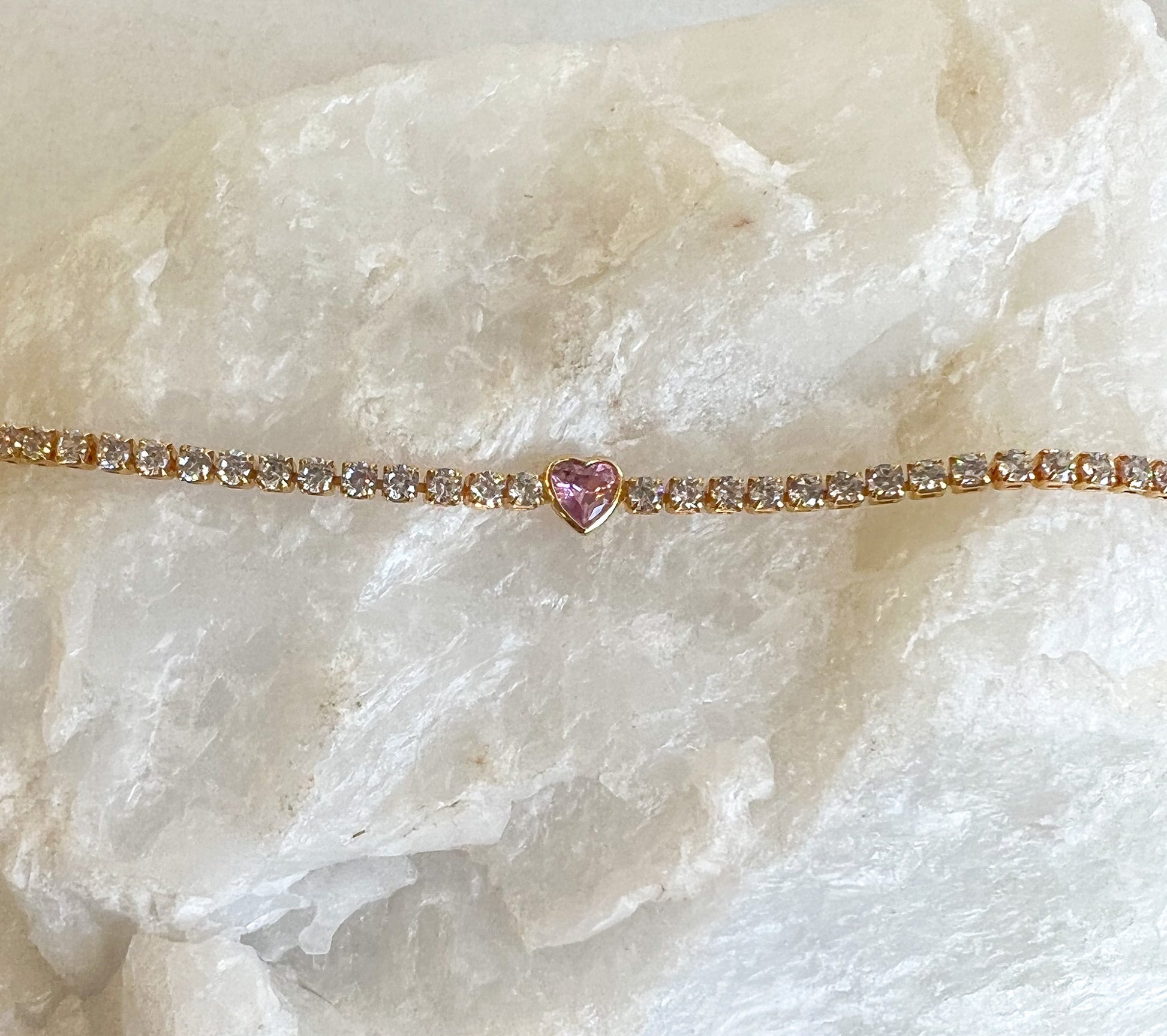 White diamond tennis bracelet with bezel set pink heart gemstone in the center