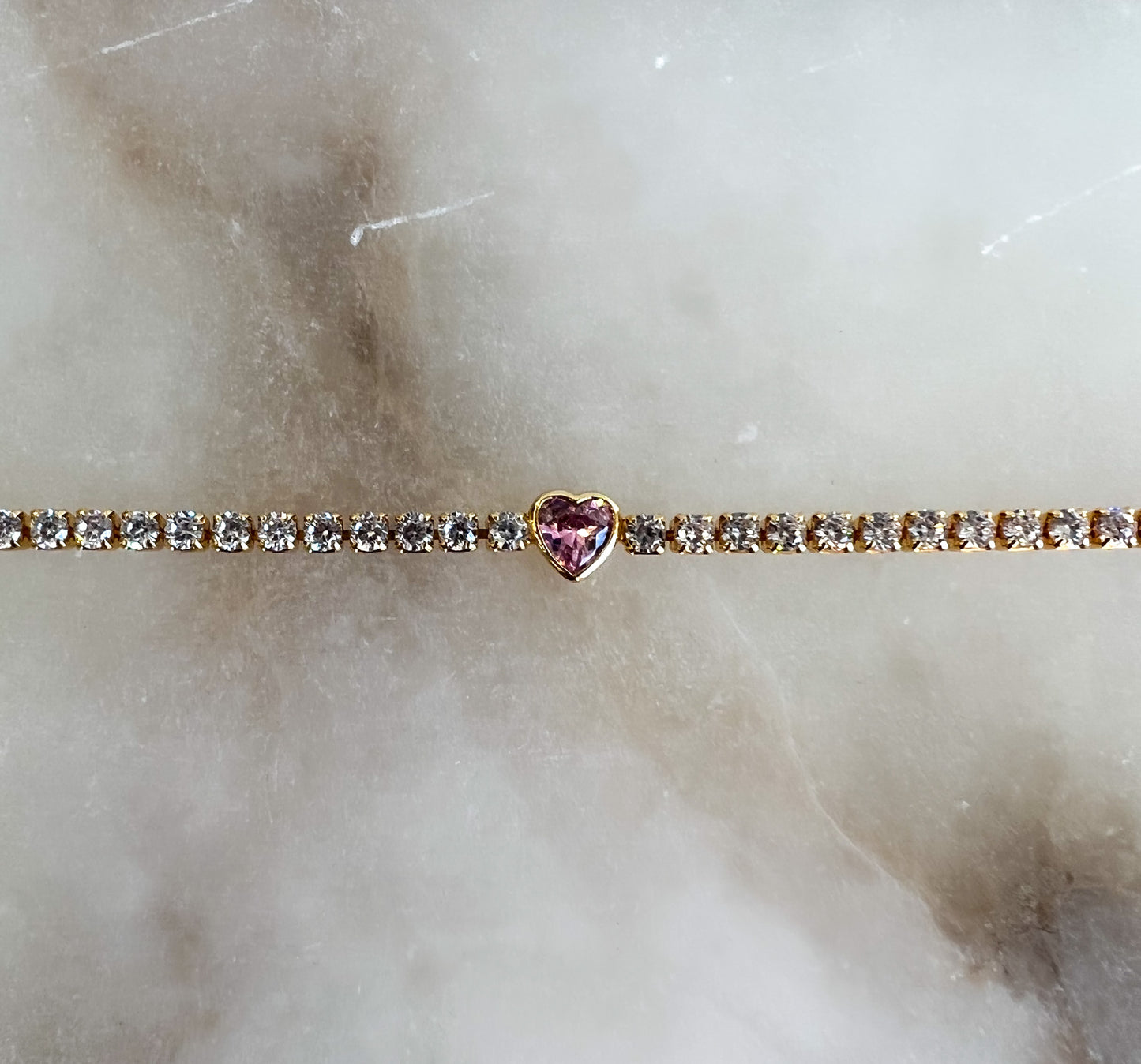 White diamond tennis bracelet with bezel set pink heart gemstone in the center