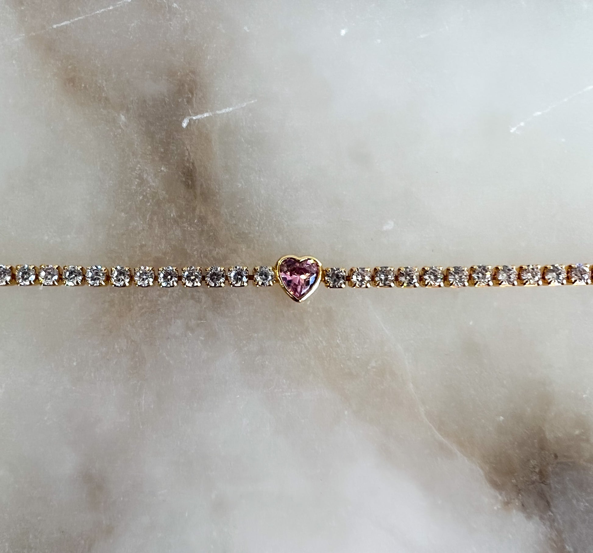 White diamond tennis bracelet with bezel set pink heart gemstone in the center
