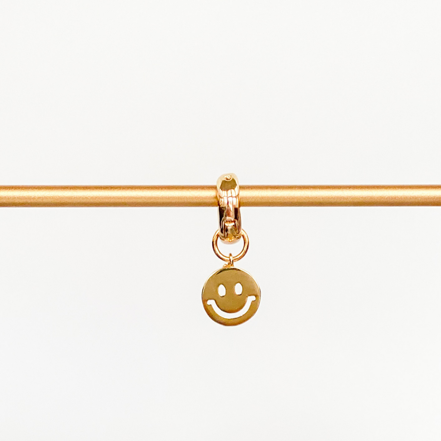 rose gold huggie with gold smily face charm